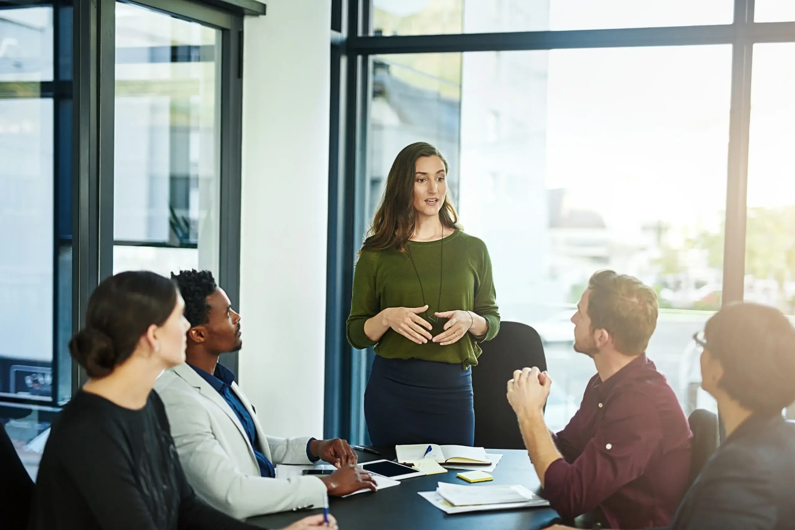 Mindful Leadership in Aktion: Junge Führungskraft steht vor Ihrem Team